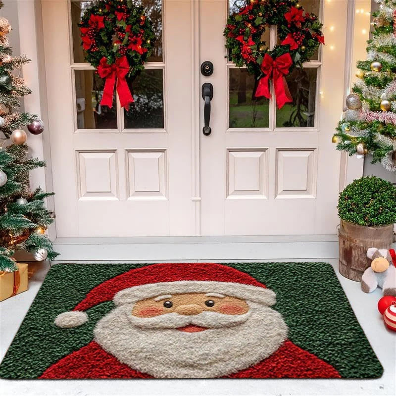 Christmas-themed door mat with Santa Claus design in front of a decorated house.