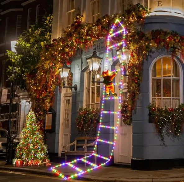 Decorative Christmas lights and wreaths on a building facade with a teddy bear figure.