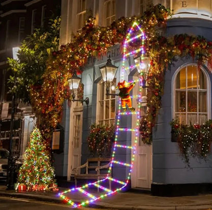 Decorative Christmas lights and wreaths on a building facade with a teddy bear figure.
